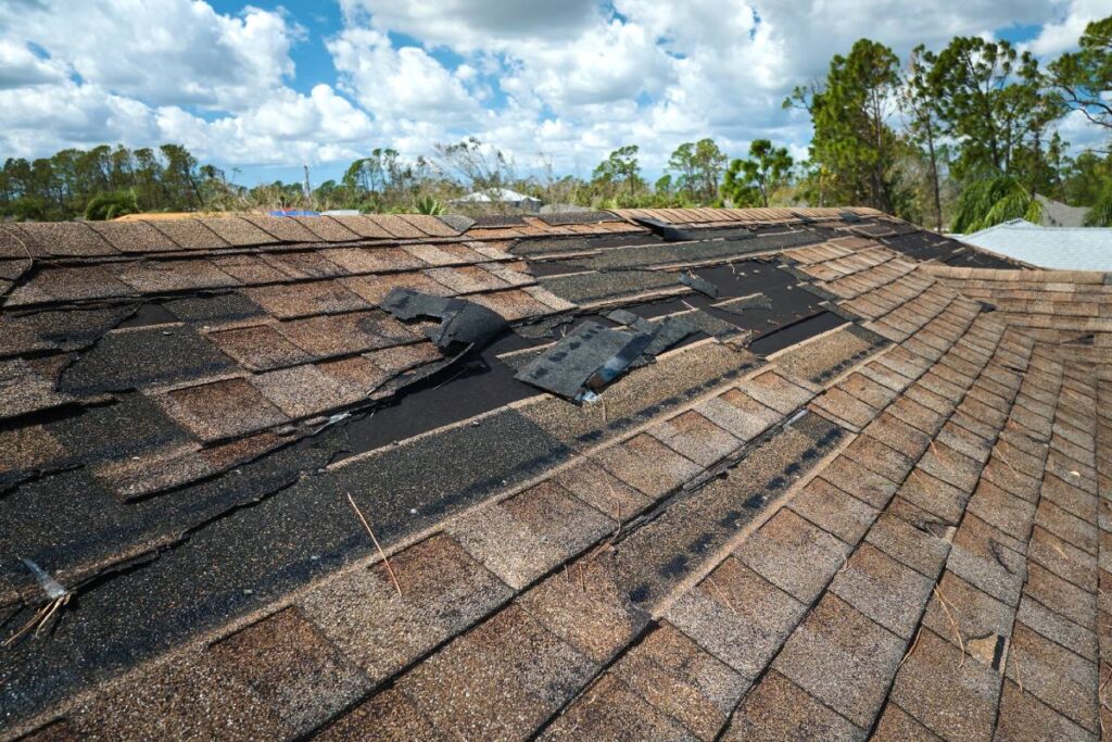 Damaged house roof with missing shingles after hurricane Ian in Florida. Consequences of natural disaster.