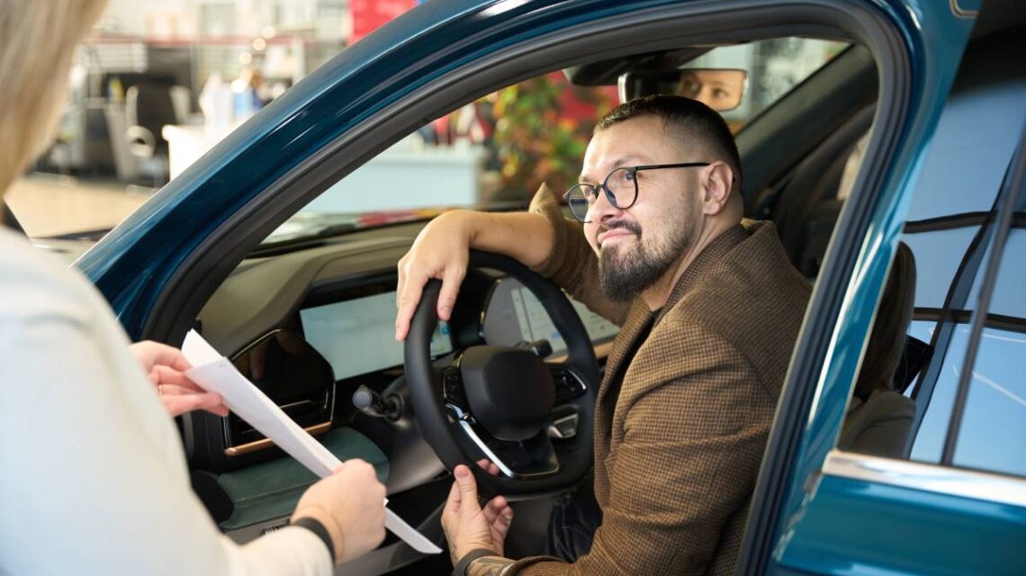 Man sitting behind the wheel of a car communicates with the seller