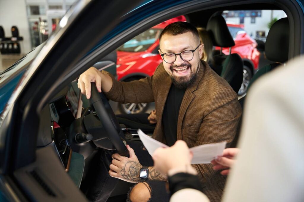 Young guy laughs when he looks at a contract for the purchase of a new car
