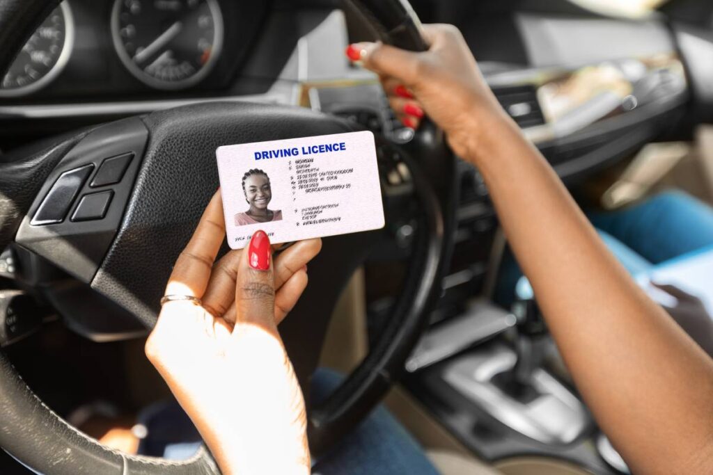 Newest driving license in unrecognizable black lady hands, closeup, african american woman driving school student celebrating successful graduation, sitting in car with instructor, cropped