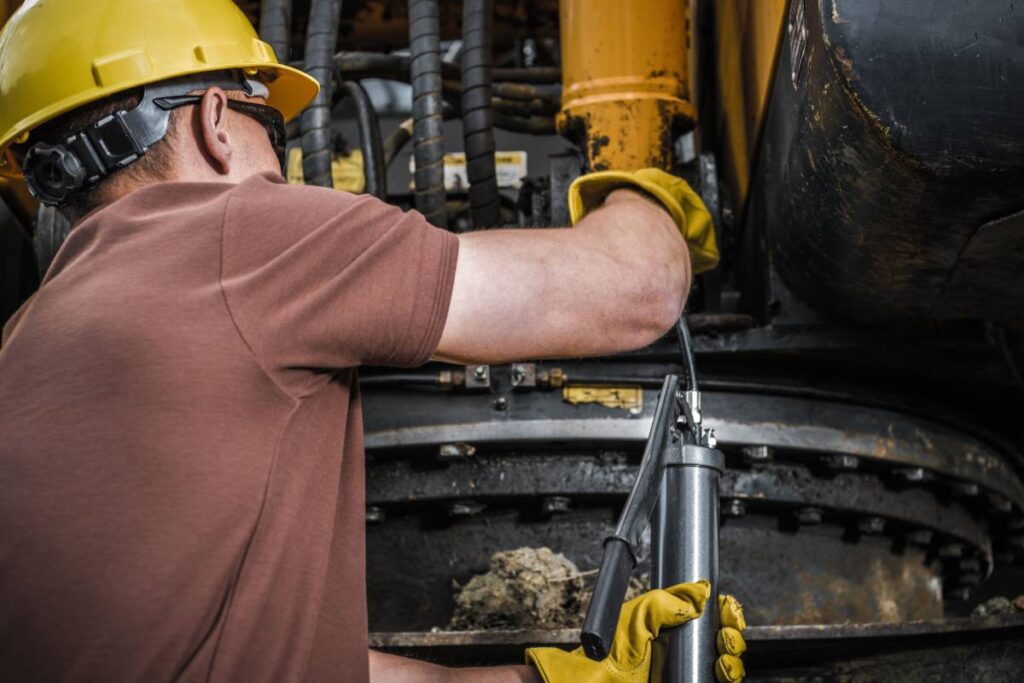 Caucasian Technician Replenish Grease with Hand Pump Gun. Heavy Duty Industrial Machinery Maintenance.