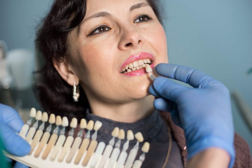 Close-up portrait of woman in dental clinic office. Dentist checking and selecting colour of the teeth, making the process of treatment. Dentistry